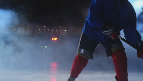 Professioneller-Eishockeyspieler-Mit-Schläger-Und-Puck-Bewegt-Sich-Auf-Luda-In-Schlittschuhen-Und-Helm-Auf-Dunklem-Hintergrund-Und-Rauch.-Dribbling-Mit-Dem-Puck-Eines-Jungen-Mannes-Auf-Der-Eisbahn